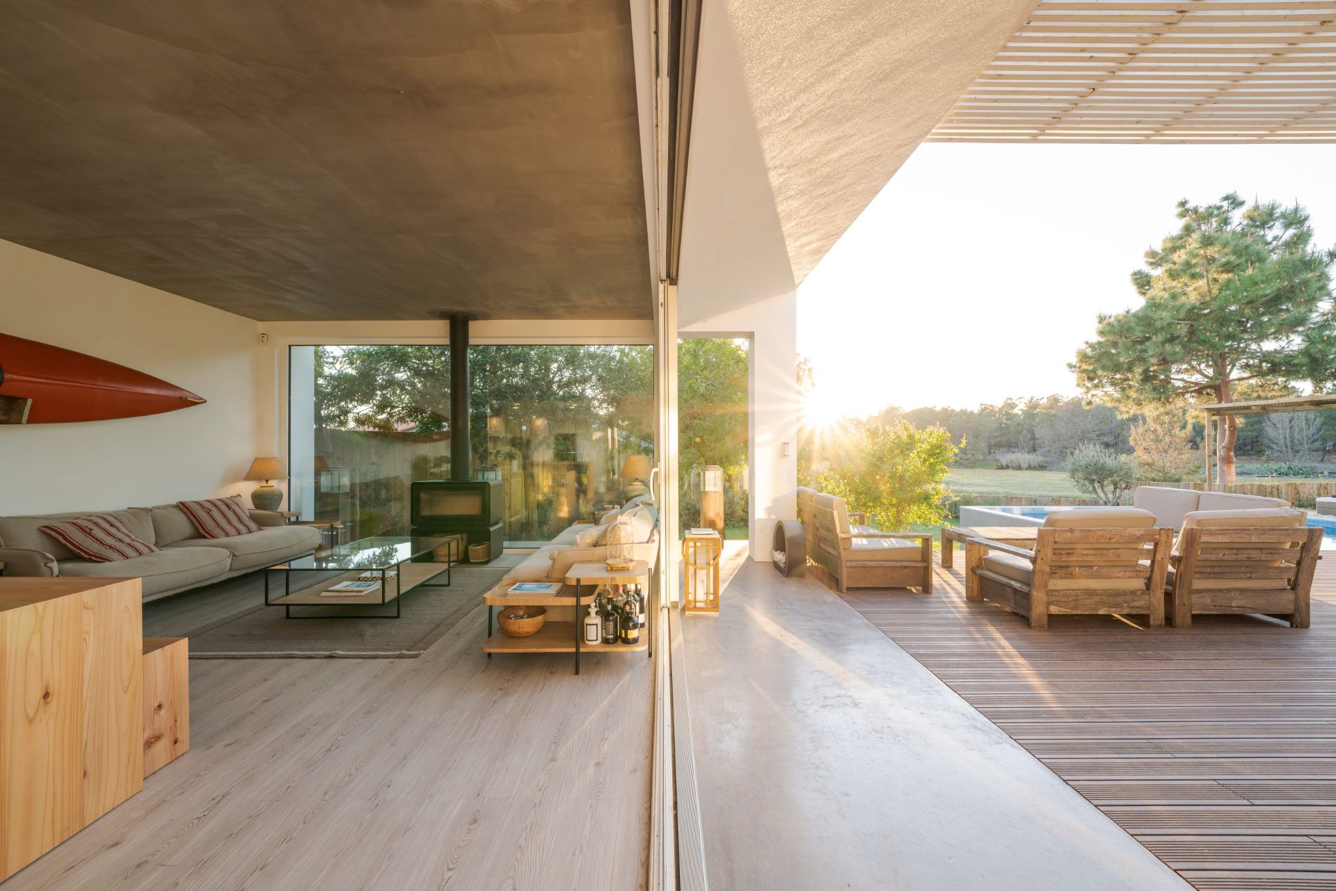 Séjour de villa contemporaine ouvert sur une terrasse avec piscine au coucher du soleil.